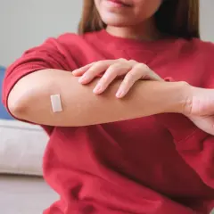 Kobieta z plastrem na łokciu, chroniącym przed wysiękiem osocza z rany.