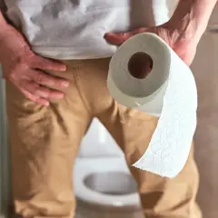 Mężczyzna trzymający rolkę papieru toaletowego, symbolizująca prawidłowe oddawanie moczu u mężczyzn i higienę.
