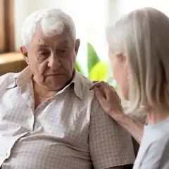 Starszy mężczyzna z wyrazem smutku na twarzy, którego pociesza kobieta. Obraz symbolizuje depresję starczą i potrzebę wsparcia.