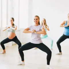 Kobiety wykonują ćwiczenia na nietrzymanie moczu, w tym przysiady. Jedna z nich jest w ciąży.